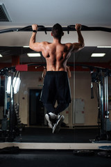 Athletic man making pull-up exercises on a crossbar in the gym