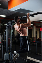 Athletic man making pull-up exercises on a crossbar in the gym