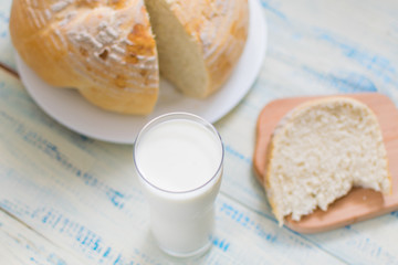 A glass of milk and white bread on a wooden background.