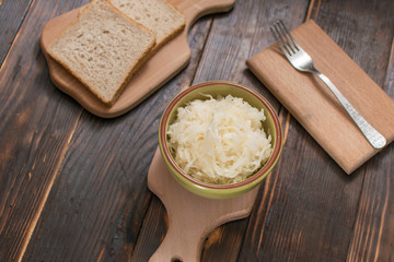 Sauerkraut in a plate on a wooden background.