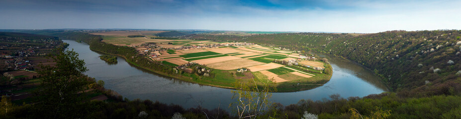 View of the village in spring from a bird's eye view. Panoramic photo of a beautiful village and fields on a peninsula surrounded by a river in the spring season.