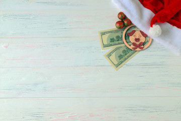 Santa Claus  hat, 100 dollar bills, a piggy toy, a symbol of 2019, and Christmas toys on a wooden light background. Money concept, Christmas, gifts, travel and shopping.