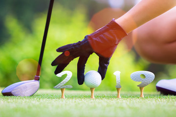 incoming year 2019, prepare by hand of woman golfer on the green,  golfball mostly ready to hit into the fairway of new year successfully, Happy new year and merry Christmas on golf course