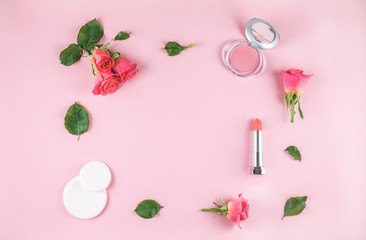 Flat lay composition with lipstick, blush, flowers.
