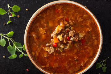 Eastern Europe traditional soup or borsch made with beef meat and vegetables on a dark slate