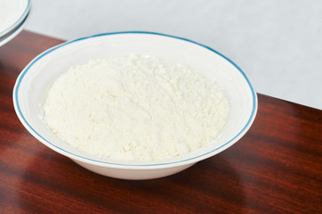 Bowl of flour on wood a table.