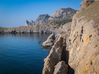 Steep beautiful mountains and azure waters of the Black Sea off the coast of the village of Novy Svet in the Crimea. Golitsyn or Falcon trail. Sunny autumn day.