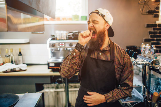 Tired Young Man Stand And Yawn. He Is Alone In Kitchen.