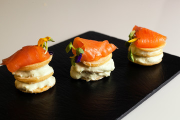 Delicious food. Pancakes with salmon on black ceramic plate