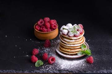 Pancakes with raspberries and berries around on black backgound