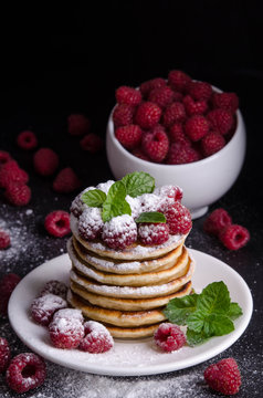 Pancakes with raspberries and berries around on black backgound