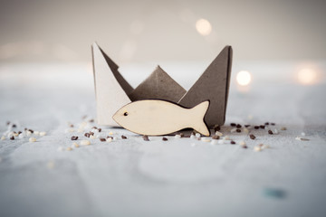 Kleiner Fisch aus Holz mit Schiffchen aus Papier als Symbol für Glaube, Reise, Ankunft