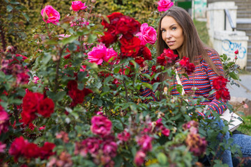 Portrait of beautiful young girl near flower bed of roses.