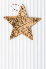 Beautiful star of birch bark on white corrugated cardboard background. Ready for Christmas greeting.