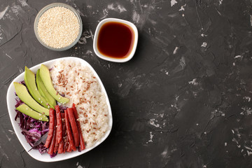 poke bowl Hawaiian food. a plate of rice, salmon, avocado, cabbage and cheese. near skunk and soy sauce on a black background. top view with space for text