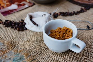 Sweetener inside a cup next to coffee beans and a strainer
