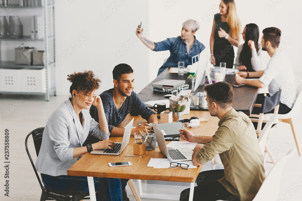 Wall mural Friends and coworkers working together at open space in advertising agency