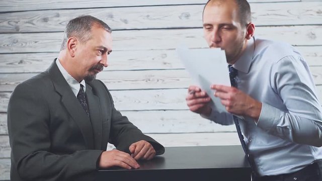 Smiling young manager persuades a client to sign a contract.