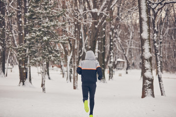 Man jogging in a cold winter snowy day outdoors.