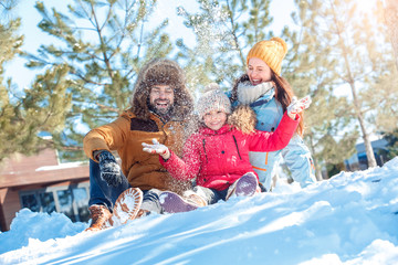 Winter vacation. Family time together outdoors sitting throwing snow laughing joyful