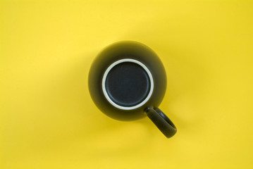 Bottom of black ceramic cup isolated in yellow