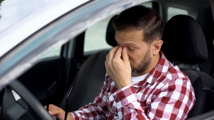 Overworked car driver taking eyeglasses off, eyesight disease, health weakness