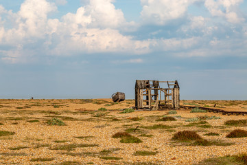 A derelict hut and boat on a pebble beach in Kent