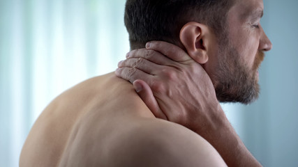 Fototapeta premium Male touching neck, feeling strong spasm upper back, pinched nerve, discomfort