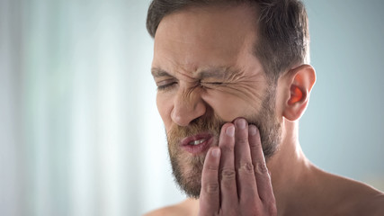 Male suffering from tooth ache, strong dental pain, pulp inflammation, decay