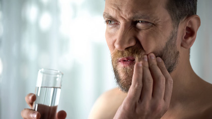 Man rinsing tooth with water, hypersensitivity, sharp dental pain, gingivitis