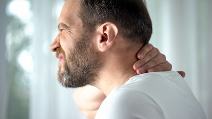 Caucasian male massaging neck, feeling discomfort, spinal problem, body care