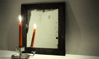 Red candle reflected in old mirror