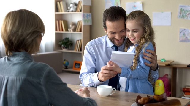 Little daughter presenting hand made greeting card to father, sincerity and love