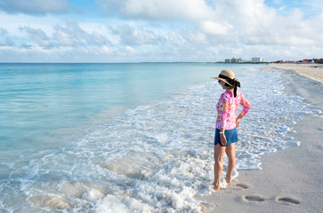 Woman Standing on a Caribbean Beach with a Short Skirt, Colorful Top and Straw Hat