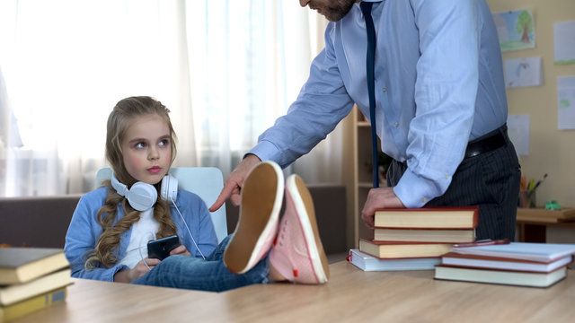 Dad Scolding His Teenage Daughter Listening To Music In Headphones, Conflict