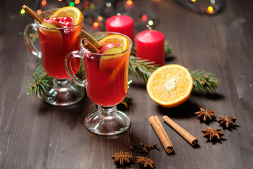 Mulled wine on a wooden background with candles, pine branches and Christmas lights. Selective focus