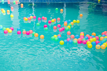 Small colorful beach balls floating in swimming pool abstract concept for pool party and summer vacations.