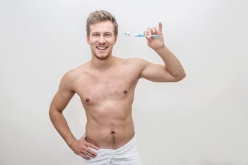 Happy and healthy young man hold tooth brush with toothpaste on it. Guy look on camera and smile....