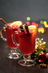 Mulled wine on a wooden background with candles, pine branches and Christmas lights.