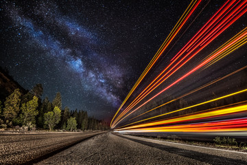 Light streaks down the highway into the milky way.