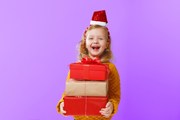 Happy little blonde child girl holding three boxes with gifts on a pink isolated background. The concept of celebrating, giving and receiving a gift