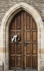 Beautiful church door  with decoration heart made of ivy.The heart with the bow hangs at the entrance gate of the church.
