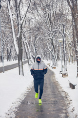 Fototapeta na wymiar Man jogging in a cold winter snowy day outdoors.