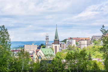Fototapeta premium Pejzaż miejski lub panorama miasta Saguenay w Kanadzie w Quebecu latem z wieżą kościoła, wieloma domami, budynkami i zielonymi drzewami parkowymi