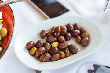 On the plate lie large, pickled Greek olives.