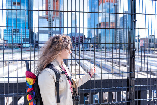 Woman tourist with rainbow LGBT LGBTQ umbrella, backpack in NYC highline, high line, urban Chelsea West Side Hudson Yards train depot