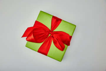 Top view of wrapped gift with red satin bow isolated on grey background