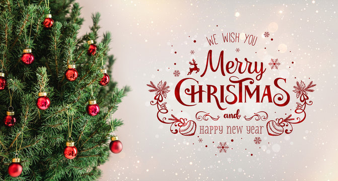 Christmas tree with red decorations and text Merry Christmas on holiday background with snow, blurred, sparking, glowing. Happy New Year and Xmas theme