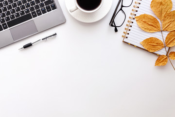 Workspace with yellow maple leaves, laptop keyboard, cup of coffee, notebook, pen and glasses. Top view of cozy office desk. Autumn copy space background, flat lay...