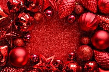 Red Christmas frame. Christmas balls, stars, cones and hearts on red sparkles background. Flat lay....
